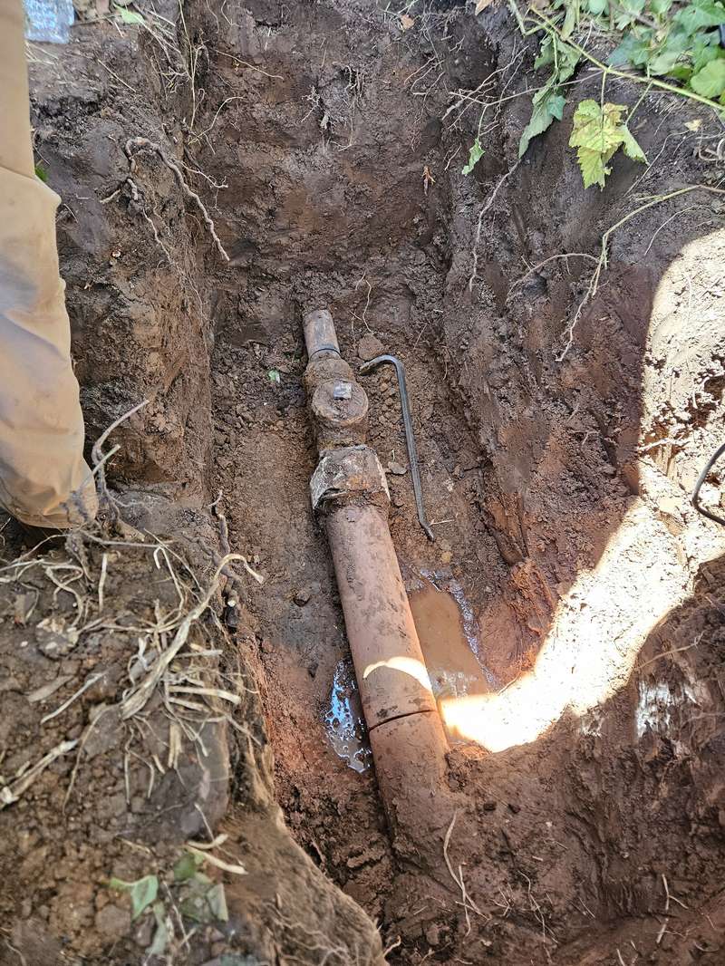 drainage-service-old-clay-sewer-pull-orange-county Excavated corroded clay sewer line with a cleanout fitting and standing water in the trench