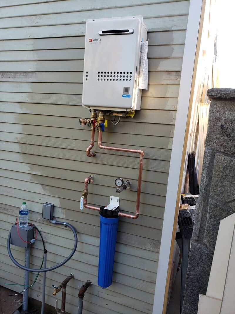 noritz-tankless-exterior-wall-install-orange-county A Noritz tankless on the exterior wall of a garage in Orange County, the “pop it outside” pattern that removes the venting question and gives floor space back.