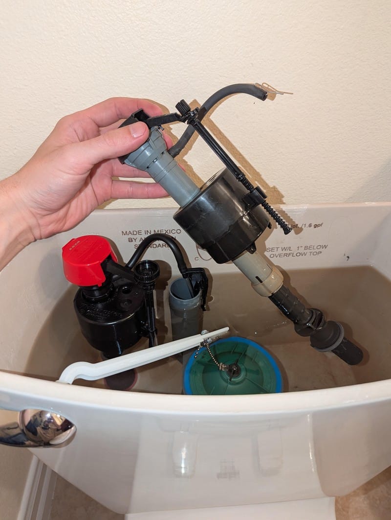 repair-service-toilet-fill-valve-flapper-replacement Replacement fill valve and flapper being installed inside an open toilet tank during an Orange County repair call
