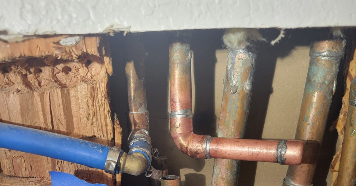 slab-leak-corroded-copper-supplies-in-slab-orange-county Cut copper supply lines marked with blue tape reading "1/2 laundry" and "1/2 leak from main manifold" during slab leak diagnosis