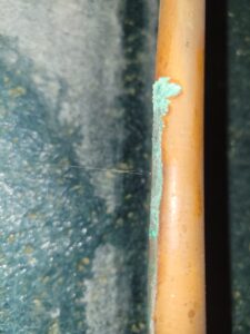 slab-leak-pinhole-copper-water-spraying-orange-county Pinhole leak spraying a fine stream of water from a corroded copper pipe with green corrosion buildup
